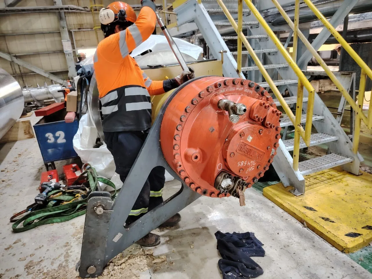 Trabajador de MACK junto a un reductor naranja en una planta industrial