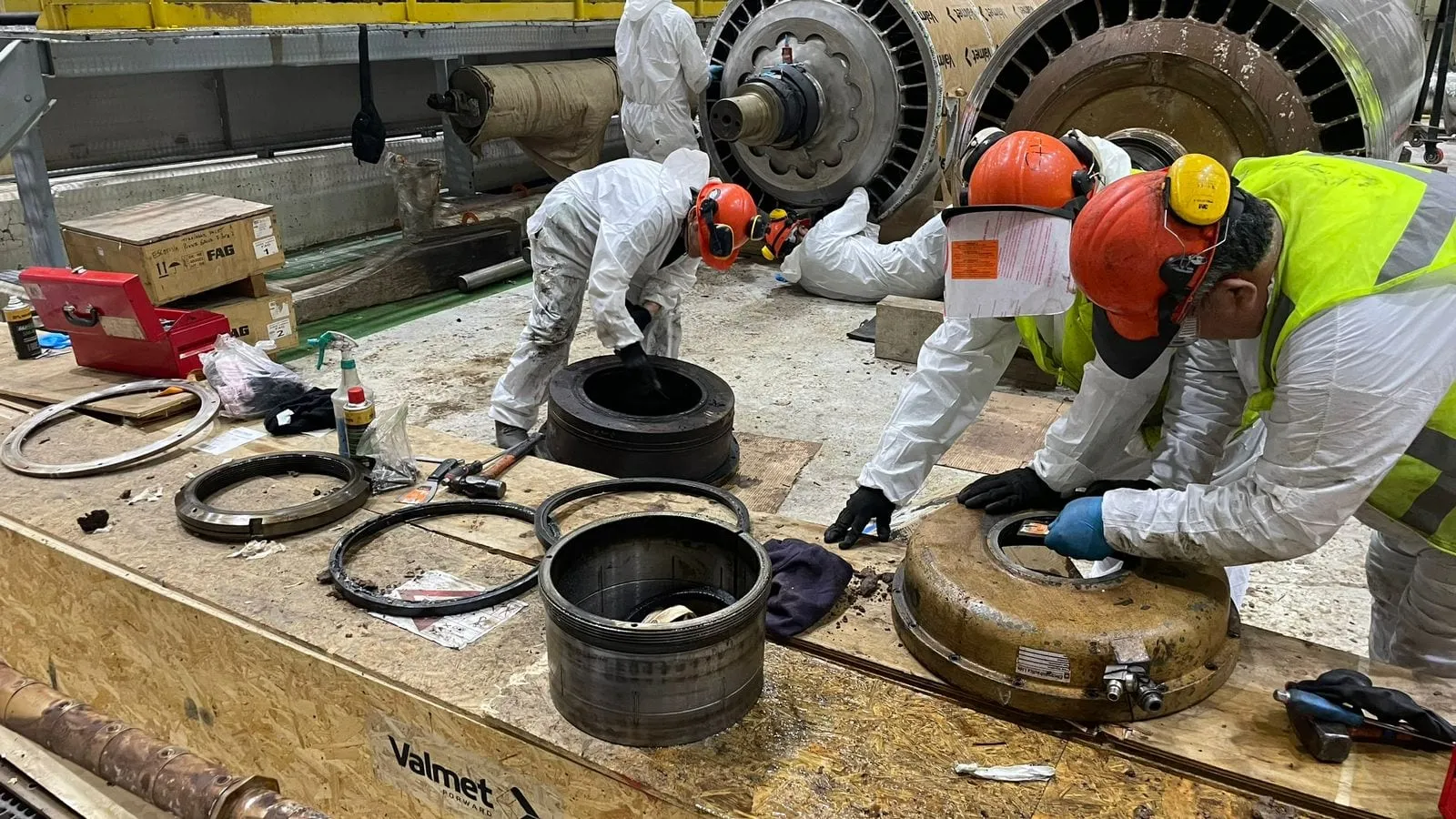 Personal de MACK con trajes de protección trabaja sobre piezas de un equipo Valmet