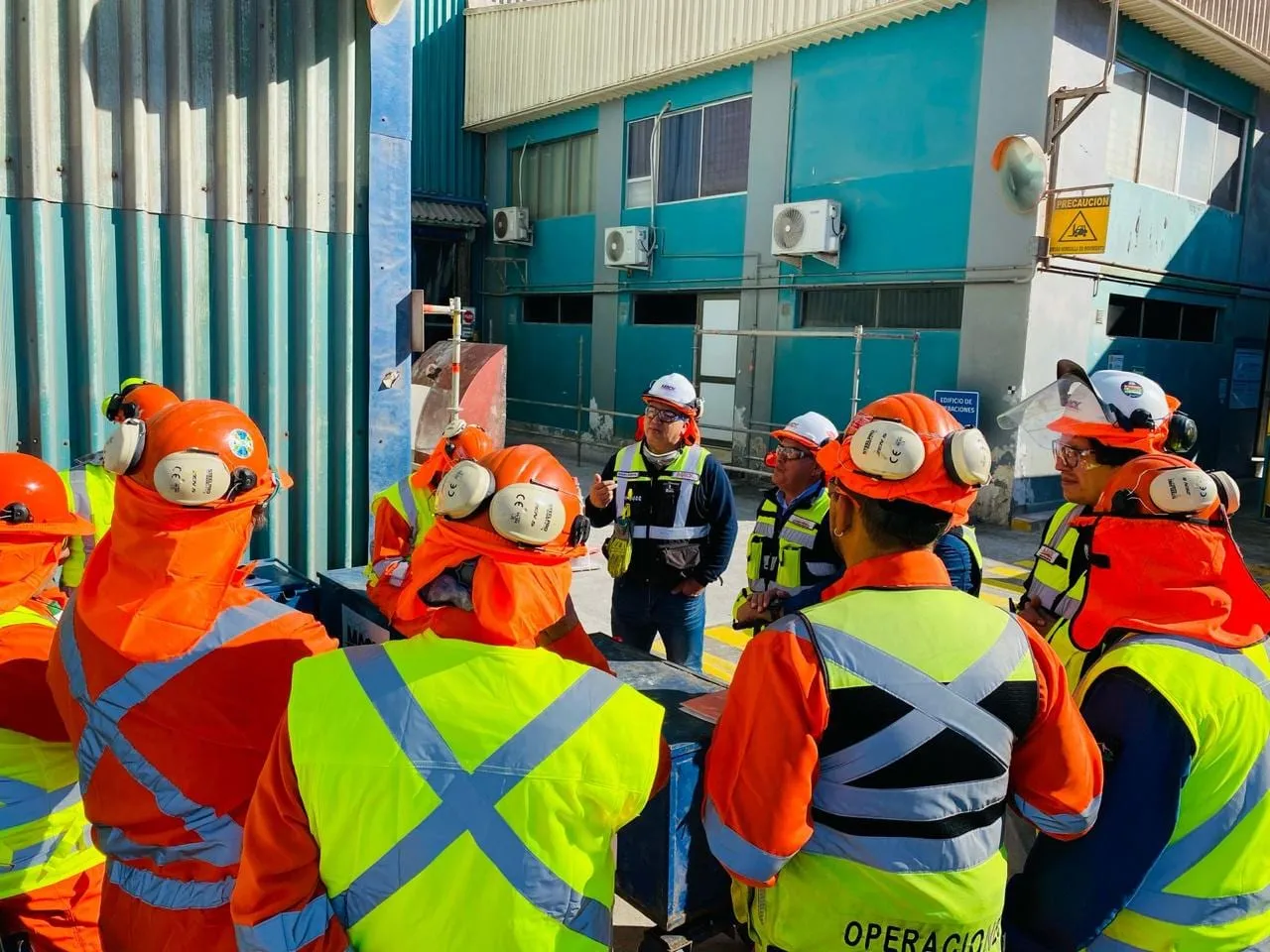 Equipo de MACK con cascos y chalecos reflectantes reunido en una planta